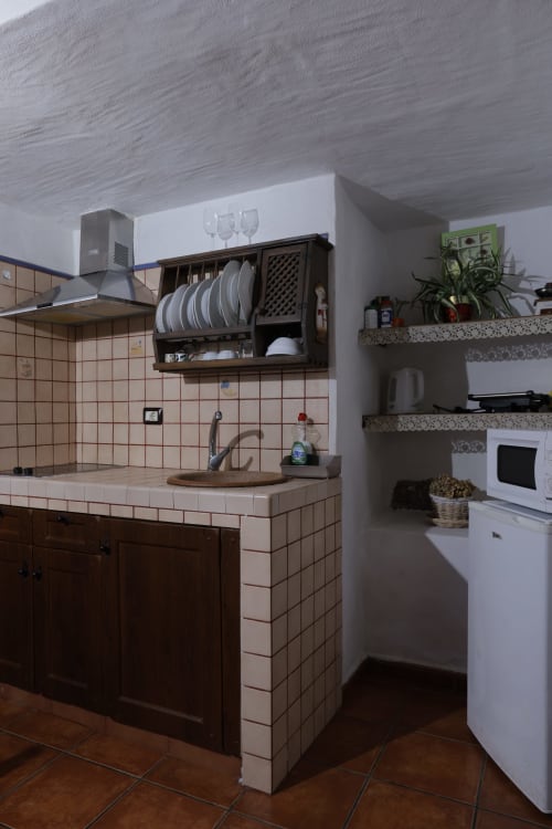 Compact cottage kitchen at Casonas de Marengo with cream tiles, dark wood cabinets, plate rack, and white appliances