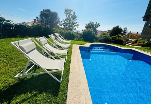 Tumbonas blancas en jardín verde junto a piscina azul en la villa Vila Arume de Baiona
