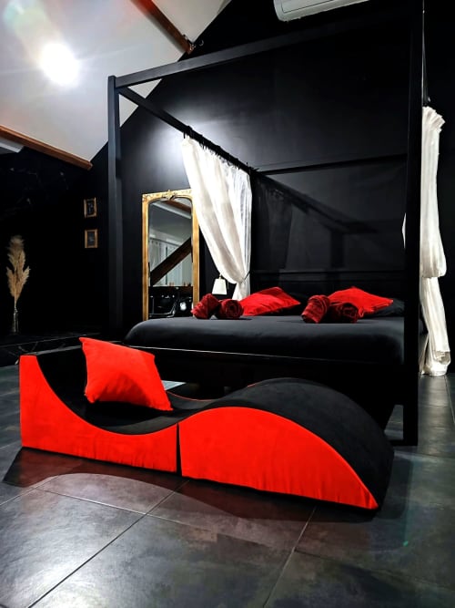 Chambre moderne à Lesdoucesnuits45 à Montargis avec lit à baldaquin noir, accents rouges et miroir doré