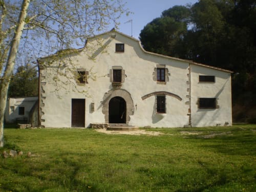 Esterno dell'ostello rurale Can Ricó a Vallgorguina, Barcellona - edificio in pietra bianca con ingresso ad arco