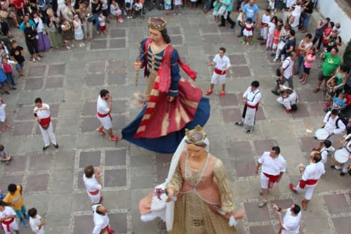 Figure giganti sfilano attraverso la piazza del villaggio durante la celebrazione del festival di Vallgorguina vicino a Can Ricós