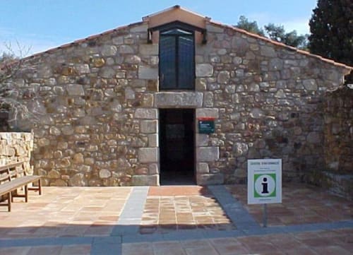Facciata in pietra dell'ostello rurale Can Ricós a Vallgorguina, Barcellona, con ingresso e cartello informativo
