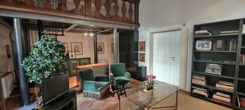 Elegante soggiorno nella Suite Patrimonio dell'Umanità di Assisi con sedute in velluto verde, scaffali scuri e vista sulla città