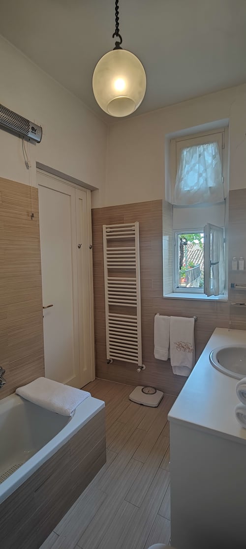 Bagno moderno nella villa di Assisi con pareti a texture legno, portasciugamani bianco, vista dalla finestra, lampada a sospensione e lavabo
