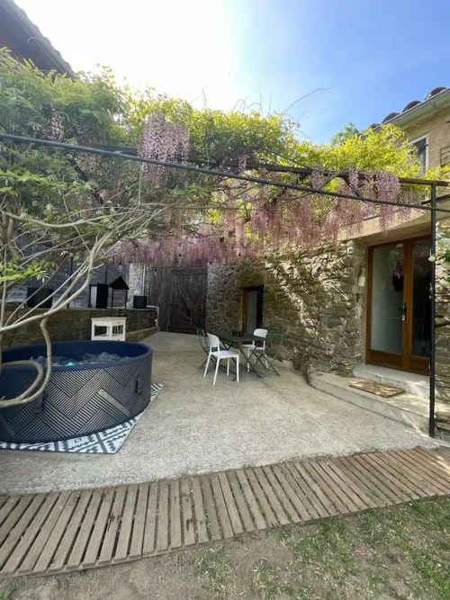 Patio de la cour du Mas de Dieusse, gîte à Saint Bres : bâtisse en pierre, glycine, salon extérieur et bain à remous