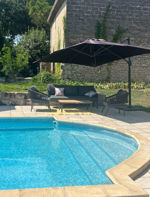 Luxurious poolside seating at La Conciergerie De Franck villa in Boissières with black umbrella and comfortable lounge