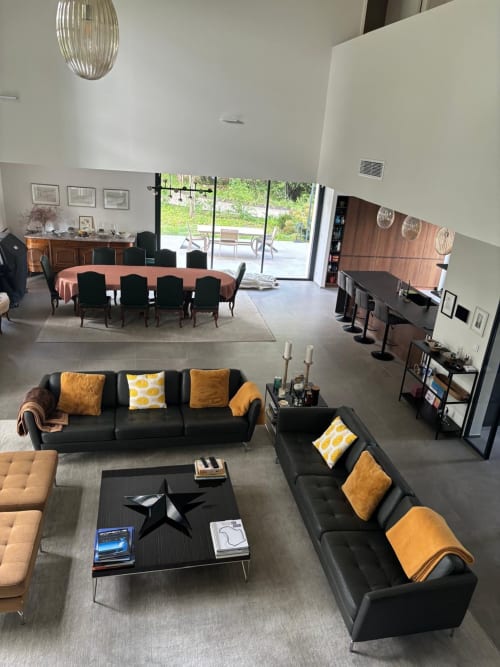 Modern villa living area at La Conciergerie De Franck with black sofas, gold accents, and large glass doors opening to pool