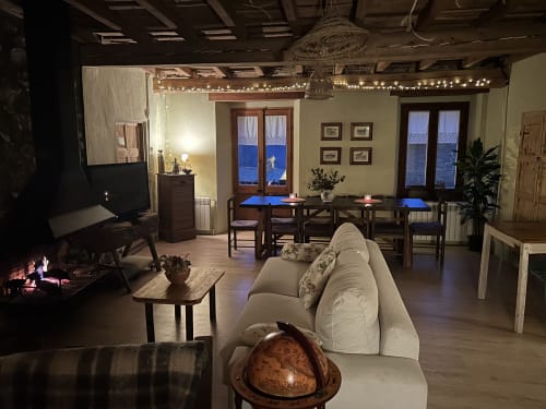 Amplio interior de la cabaña Casa Tapiolas con sofá color crema, comedor, chimenea y vistas a las montañas