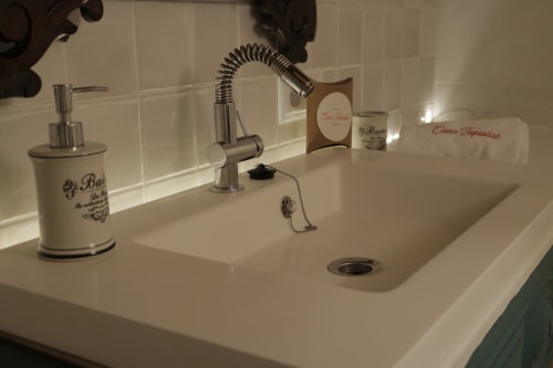 Lavabo moderno con grifo cromado, dispensador de jabón y elementos decorativos en la casa rural Casa Tapiolas en Molló