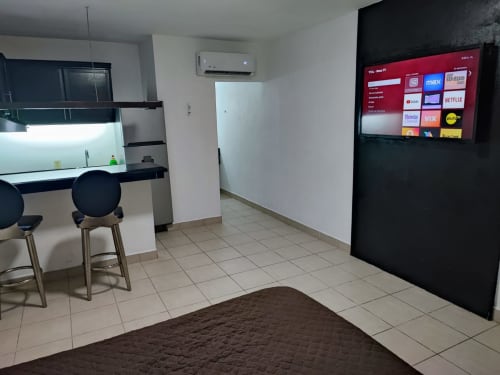 Habitación moderna del Hotel Estrella en Matamoros con kitchenette, barra, TV de pared y piso de cerámica.