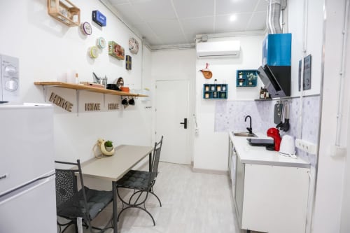 Cocina compacta en apartamento de Apartamentos Huelintown Málaga con mesa de comedor, electrodomésticos blancos y pared decorativa