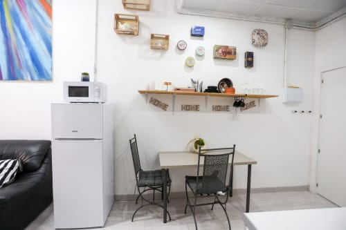 Kitchenette de Apartamentos Huelintown con mesa de comedor, refrigerador, microondas y estanterías en Málaga