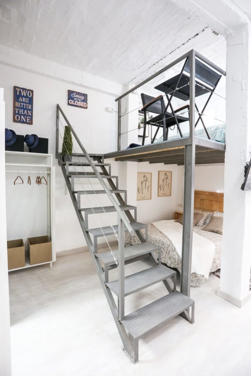 Moderno loft en Huelintown, Málaga, con escalera metálica, zona de descanso elevada y vistas a la ciudad