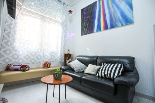 Moderno salón de apartamento en Apartamentos Huelintown, Málaga, con sofá de cuero negro, arte colorido y vistas a la ciudad