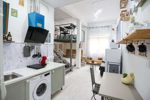 Moderna cocina y sala de estar en apartamento de Apartamentos Huelintown, Málaga con gabinetes blancos y campana azul