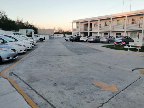 Estacionamiento del Hotel Estrella con vehículos blancos y edificio de dos pisos al atardecer en Matamoros