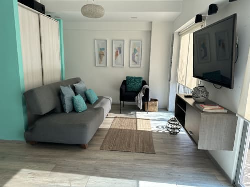 Moderna sala de estar en Pares Homes CDMX con sofá gris, detalles en turquesa, TV e iluminación natural