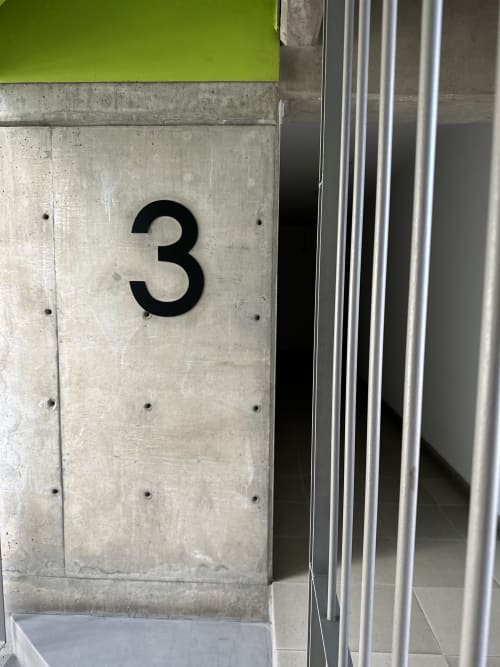 Entrada del Apartamento 3 en Pares Homes, Ciudad de México - pared de concreto con número negro y marco de puerta metálica