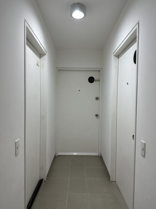 Pasillo moderno con dos puertas blancas en apartamento Pares Homes de la Ciudad de México, piso de azulejos e iluminación de techo