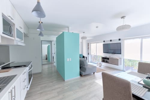 Apartamento moderno de planta abierta en Pares Homes CDMX con pared de acento turquesa, cocina, sala y grandes ventanales