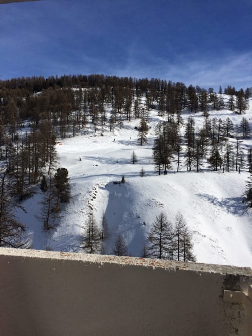 "Vue du balcon de l'appartement à Vars-les-Claux, offrant un panorama spectaculaire sur les pistes de ski enneigées, parfait pour profiter de l'air frais de la montagne et admirer le paysage hivernal."