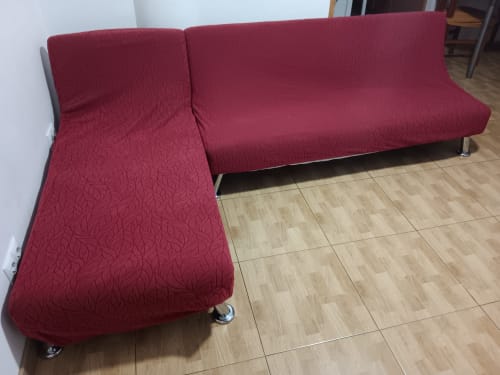 Red upholstered L-shaped sofa with metal legs in Casa Ferrer Barcelona apartment living room
