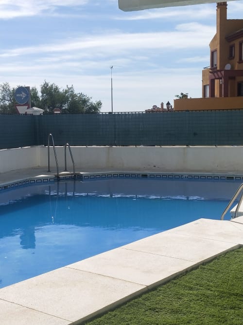 Piscina azul con tumbonas en el apartamento Wehost Costaluz de Puerto Santa María, España