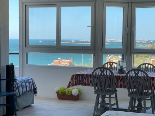 Balcón con vistas al mar, mesa de comedor y sillas con vista a la costa de Puerto Santa María y aguas del Mediterráneo