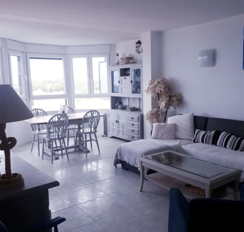 Luminoso apartamento moderno en Puerto Santa María con balcón vista al mar, comedor, sofá y mobiliario elegante