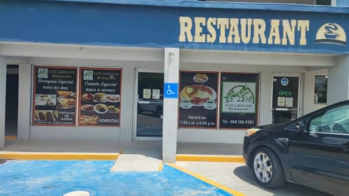 Fachada del Restaurante Los Grillos en Matamoros con señalización azul, área de comedor y horario de atención visible