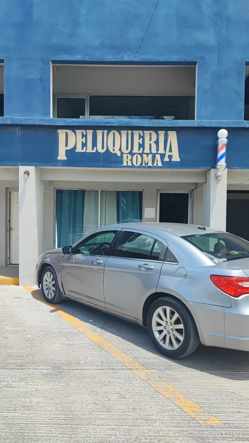 Fachada de la Peluquería Roma en Matamoros con un sedán plateado estacionado afuera
