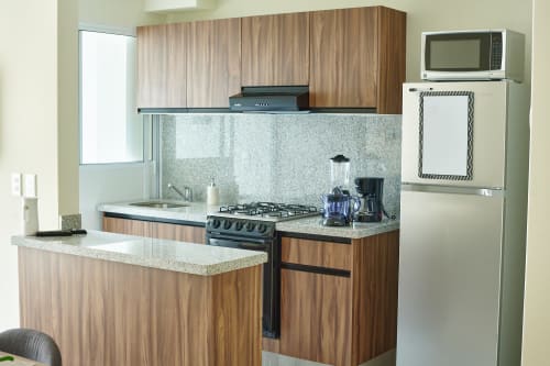 Cocina moderna con gabinetes de madera, encimeras de granito, estufa a gas y electrodomésticos de acero inoxidable en apartamento Pares Homes