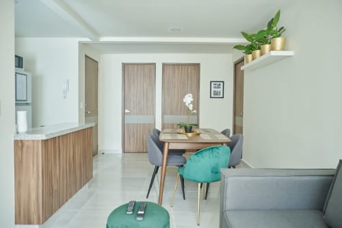 Moderno departamento en CDMX de Pares Homes con mesa de comedor, sillas en tonos turquesa, muebles de madera y decoración con plantas