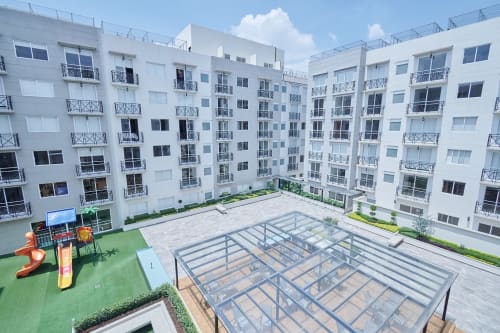 Patio moderno de complejo residencial blanco en CDMX con zona de juegos y terraza cubierta en Pares Homes