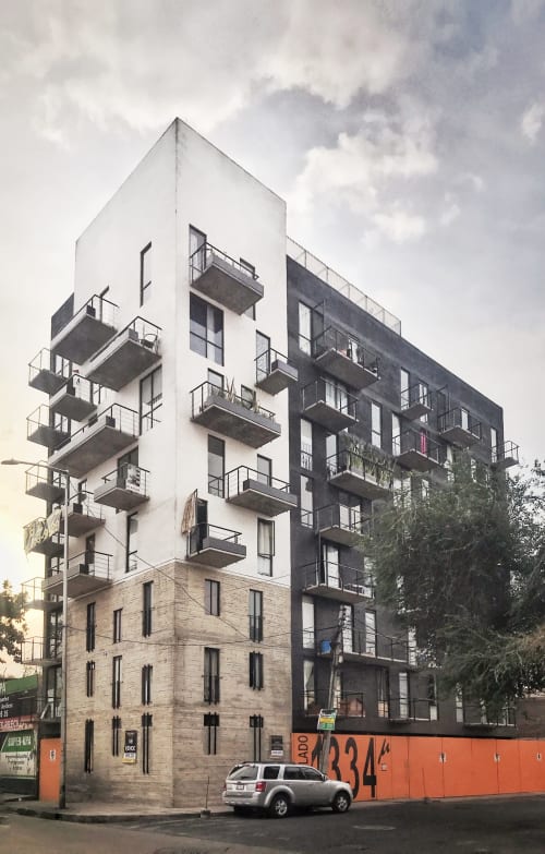 Edificio moderno en CDMX con fachadas blancas y oscuras, balcones y base de piedra a nivel de calle