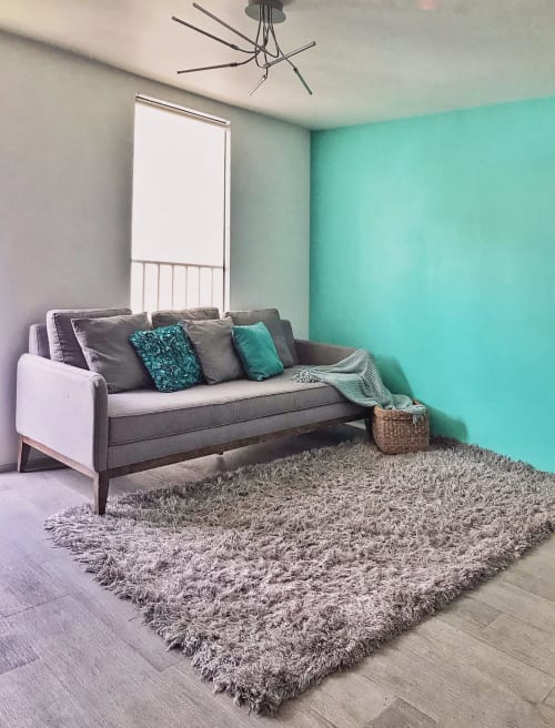 Sala moderna de Pares Homes CDMX con pared turquesa, sofá gris, alfombra texturizada y techo contemporáneo