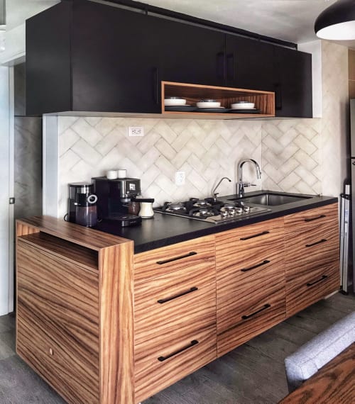 Cocina moderna en departamento de Pares Homes Ciudad de México con gabinetes de madera, encimera negra, salpicadero en espiga y estufa