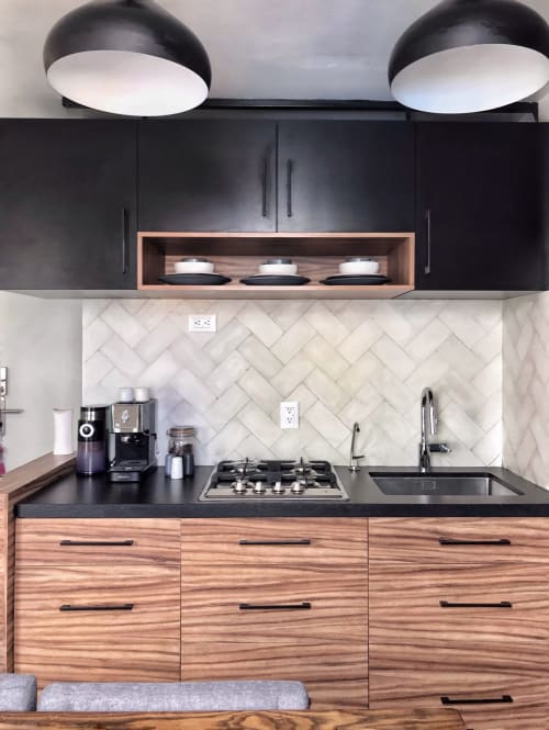 Cocina moderna en apartamento de Pares Homes Ciudad de México con gabinetes negros, cajones de madera, salpicadero de mármol y estufa a gas