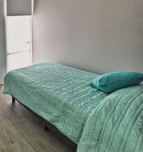 Dormitorio minimalista en apartamento Pares Homes en CDMX con ropa de cama y almohada verde salvia