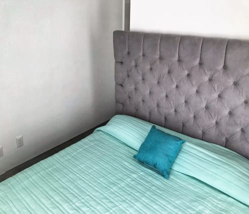 Recámara moderna en apartamento Pares Homes, CDMX con cabecera capitonada gris, ropa de cama turquesa claro y almohada de acento verde azulado