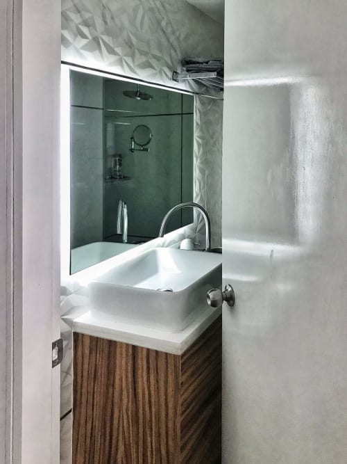 Baño moderno en apartamento Pares Homes, CDMX con lavamanos blanco, espejo iluminado y ducha con azulejos verdes