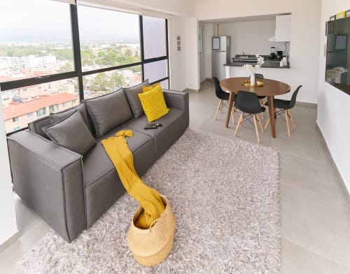 Moderno departamento en CDMX en Pares Homes con sofá gris, comedor, vistas a la ciudad a través de ventanales de piso a techo, y