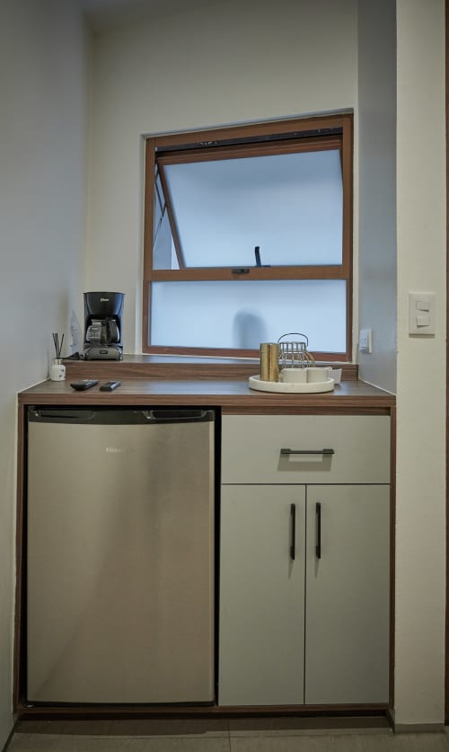 Kitchenette en habitación Pares Homes Ciudad de México con electrodomésticos acero inoxidable, gabinetes de madera y vista a ventana