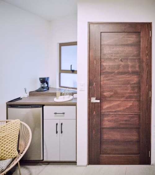 Espacio de trabajo moderno en habitación de hotel Pares Homes CDMX con puerta de madera, escritorio y ventana