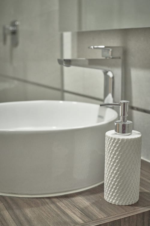 Lavamanos moderno con dispensador de jabón de cerámica blanca en habitación de hotel Pares Homes, Ciudad de México