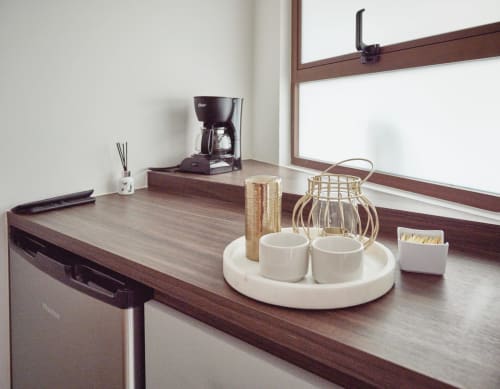 Moderno kitchenette de hotel en Pares Homes con cafetera, tazas blancas y encimera de madera natural en Ciudad de México