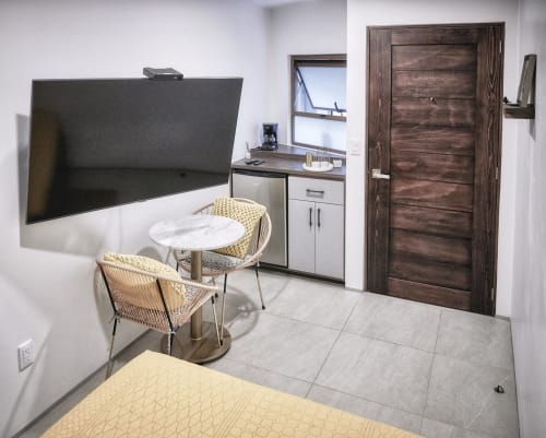 Habitación moderna en Pares Homes CDMX con TV de pantalla plana, kitchenette, mesa de mármol redonda con sillas y madera oscura