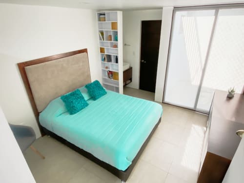 Recámara moderna en apartamento de la Ciudad de México en Pares Homes con ropa de cama turquesa, cabecera de madera, estantes blancos y puertas corredizas de vidrio
