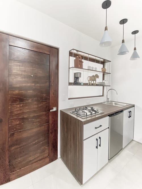 Moderna cocina en departamento de CDMX en Pares Homes con estufa de gas, fregadero, gabinetes blancos, estantería abierta e iluminación colgante