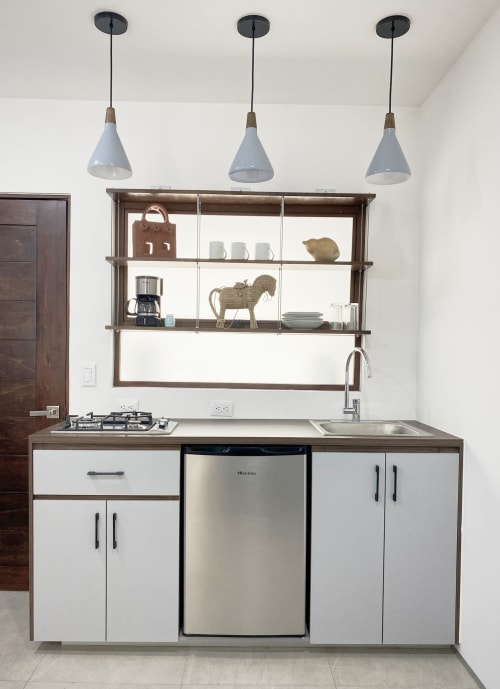 Moderna cocina con gabinetes blancos, electrodomésticos de acero inoxidable, luces colgantes y repisa mural en Pares Homes Mexico